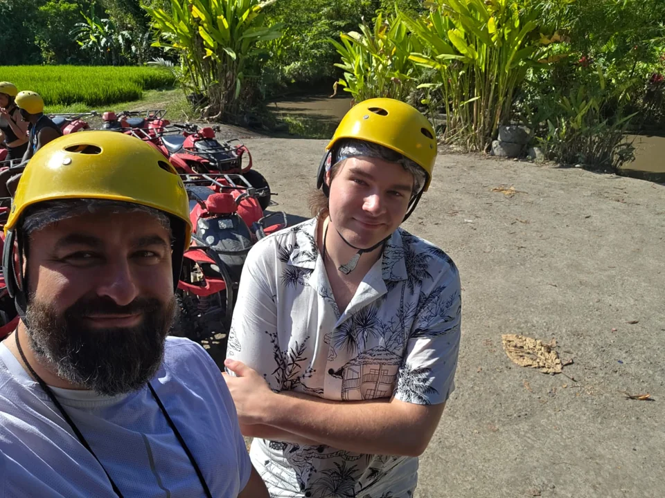 Two travellers wearing helmets, with off-road vehicles behind them