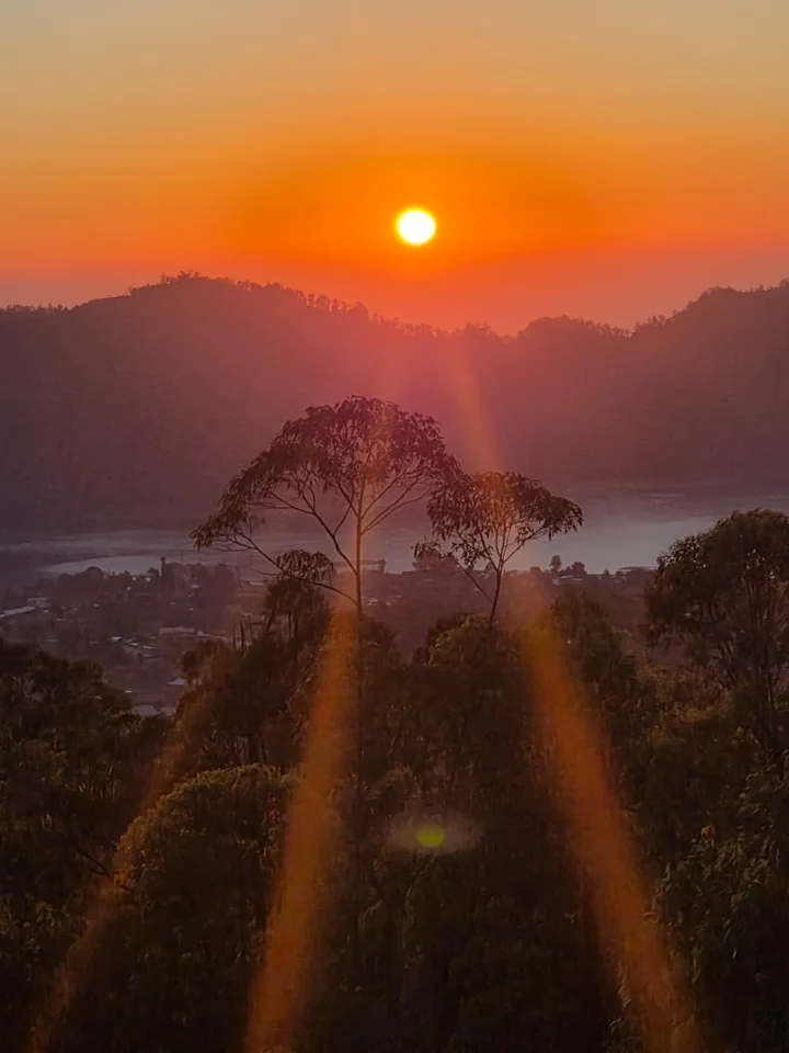 Orange sunrise above wooded hills and a lake